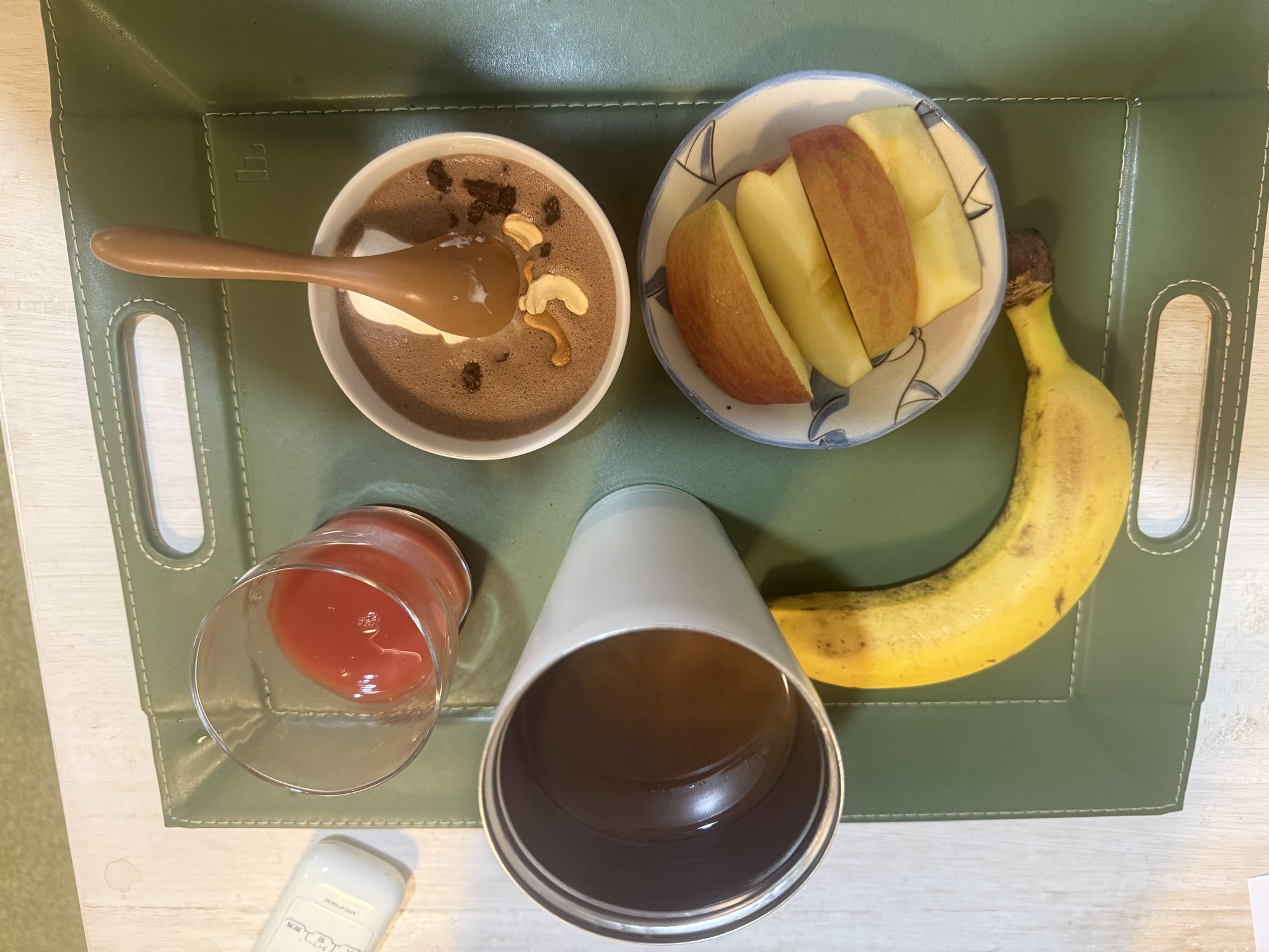 オートミールスムージー、リンゴ、バナナ、トマトジュース、お茶を並べた70代の朝食メニュー